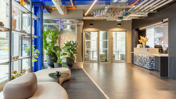 A modern office lobby with a reception desk and a large window.