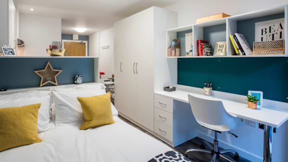 A bedroom with a bed, desk, and chair.