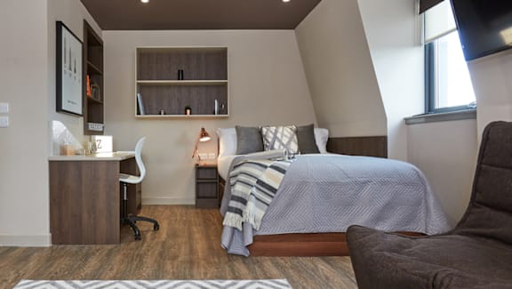 A bedroom with a bed, desk, and chair.