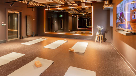 A yoga studio with mats on the floor and a large mirror on the wall.