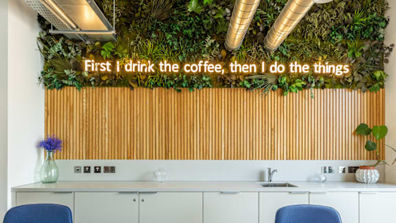 A modern kitchen with a green wall and a quote on it.