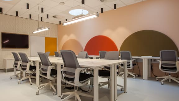 A conference room with a white table and grey chairs.
