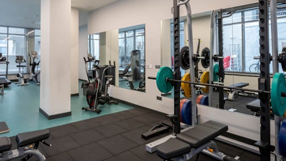 A gym with a variety of equipment including weights and treadmills.
