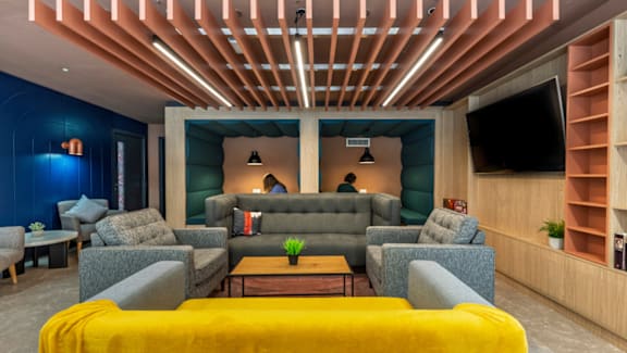 A modern living room with a yellow sofa and a wooden ceiling.