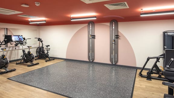 A gym with a variety of equipment including treadmills, stationary bikes, and weight machines.