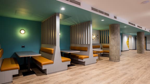 A long hallway with tables and chairs on the side.