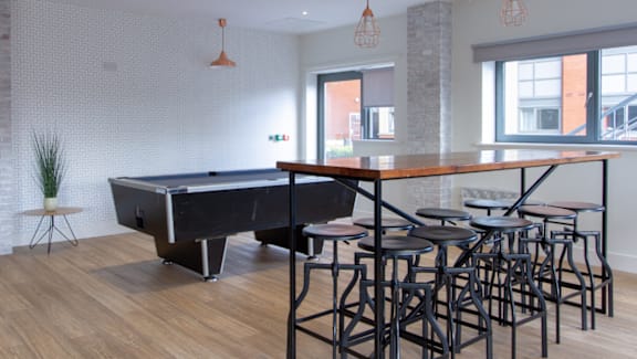 A pool table with a black cloth and a brown wooden table.