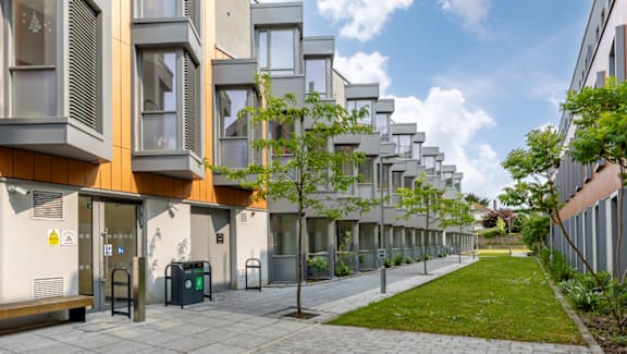 A row of modern townhouses with a green lawn in front.