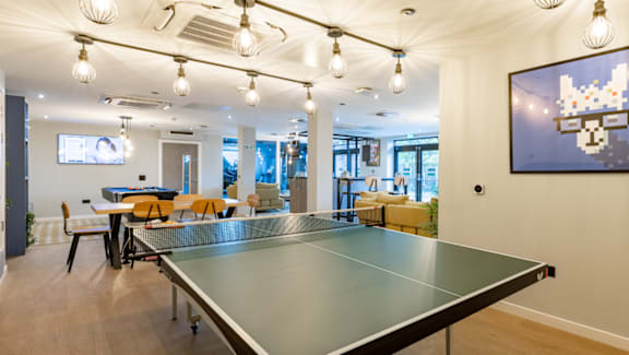 A ping pong table is in the middle of a room with a large painting hanging on the wall.