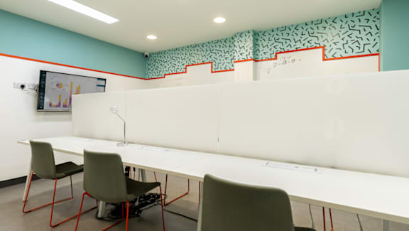 A white desk with four chairs in front of it.