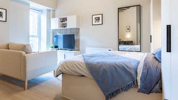 A bedroom with a bed, a couch, and a television.