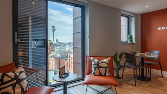 A room with a table and chairs with a view of the city.