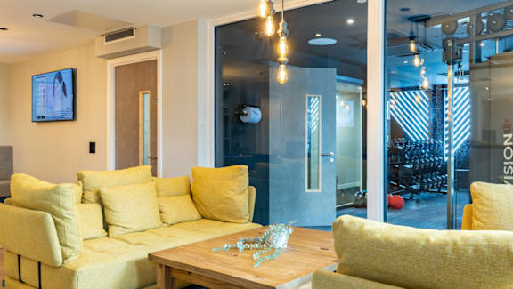 A living room with a yellow couch and a wooden table.