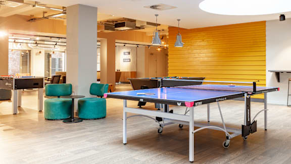 A ping pong table is in the middle of a room with a wooden wall.