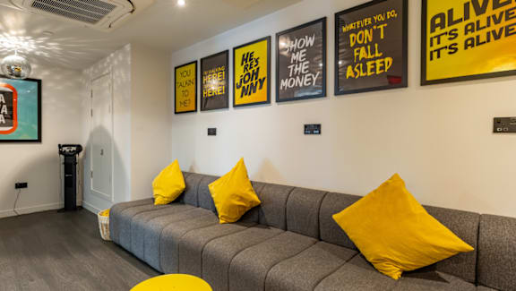 A living room with a grey couch and yellow pillows.