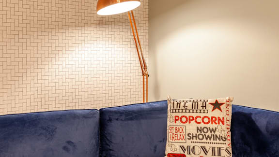 A sign advertises popcorn and movies in a room with a blue couch.