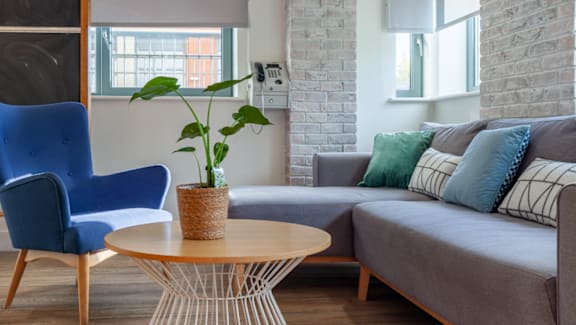 A living room with a grey couch, a blue chair, and a wooden table.