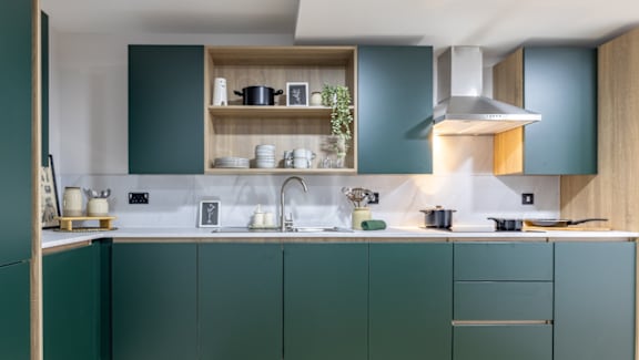A kitchen with green cabinets and a white countertop.