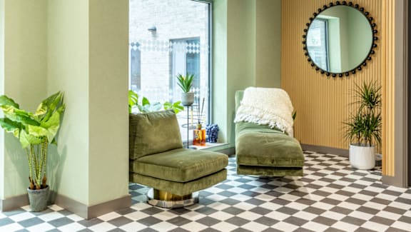 A living room with a green couch and a mirror on the wall.