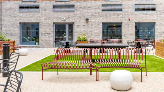 A white ball sits in front of a bench in a courtyard.