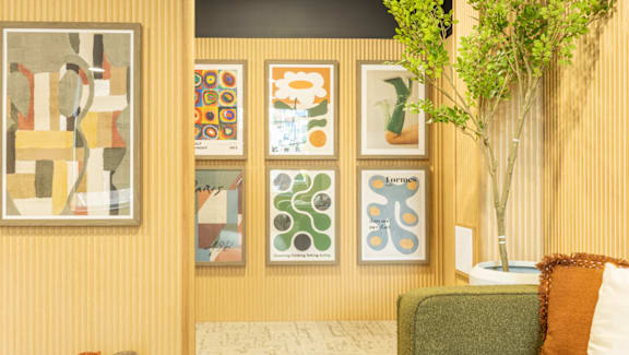 A living room with a couch and a wall of framed art.