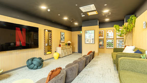 A living room with a large couch and a TV displaying the Netflix logo.