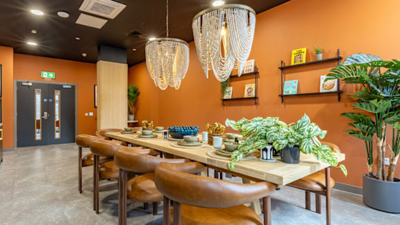 A dining room with orange walls and a wooden table.