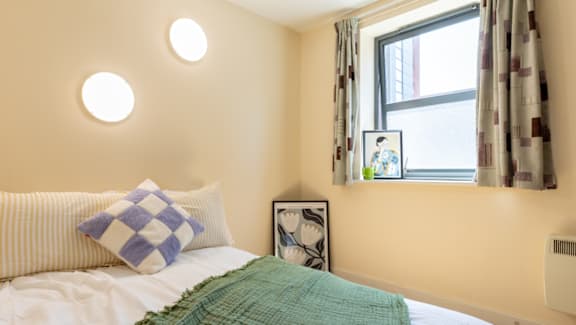 A bedroom with a bed, a window, and a picture frame on the wall.