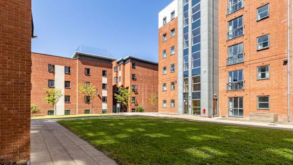 A red brick building with a green lawn in front.