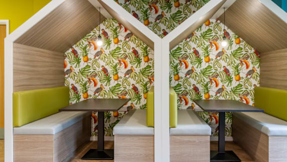 A room with a table and two benches with a wallpaper of fruits.
