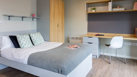 A bedroom with a bed, desk, and chair.