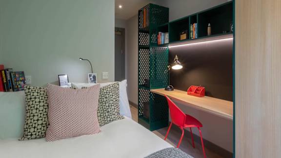 A bedroom with a bed, desk, and bookshelf.