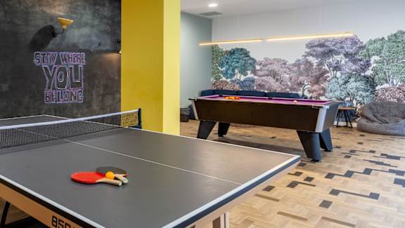 A ping pong table with a red paddle and ball on it.