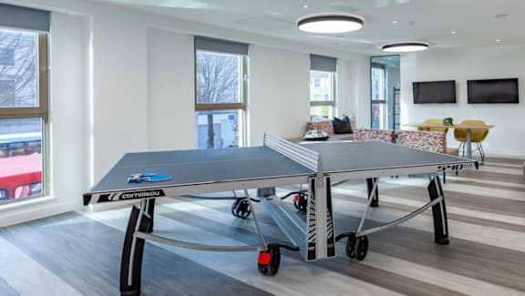 A black table with wheels is in a room with a grey table and chairs.