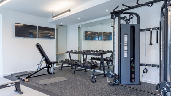 A gym with a variety of equipment including a treadmill, weights and a bench.