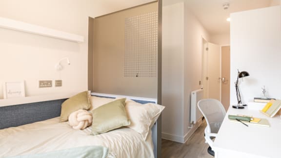 A bedroom with a bed, desk, and chair.