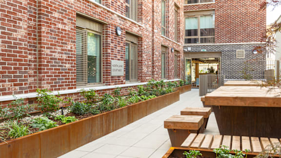 A brick building with a wooden table and benches outside.