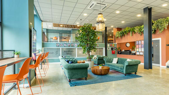 A modern office space with a green sofa set and orange chairs.