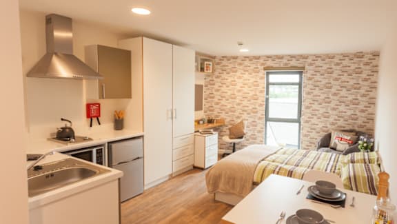 A kitchen with a sink and a bedroom with a bed.