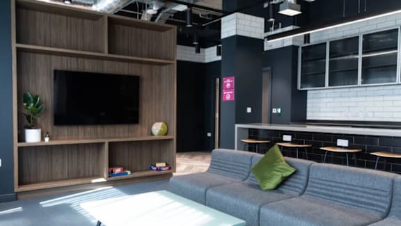 A living room with a grey couch and a wooden entertainment unit.