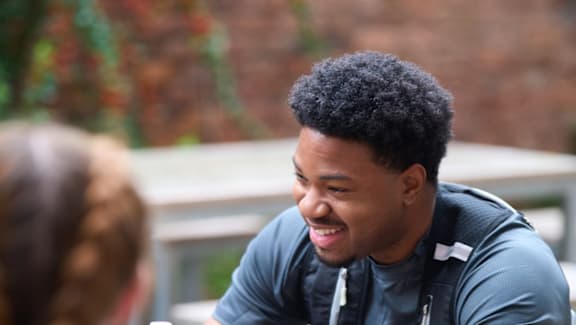 A man with a backpack is smiling at a woman.