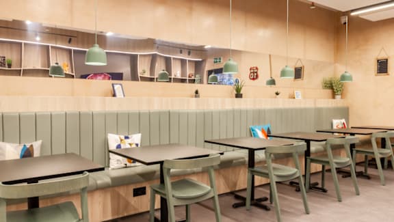 A restaurant with green chairs and tables.