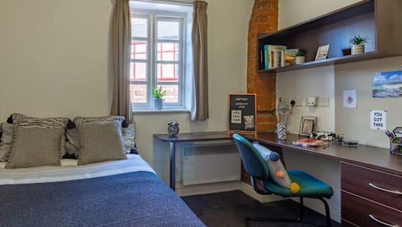 A bedroom with a bed, desk, and chair.