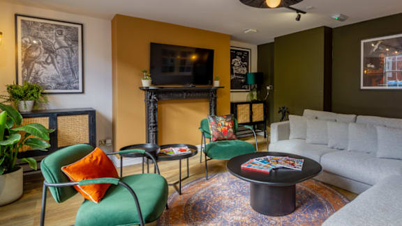 A living room with a white couch, a green chair, and a fireplace.