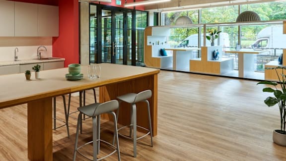 A kitchen with a bar stool and a table with a plant on it.