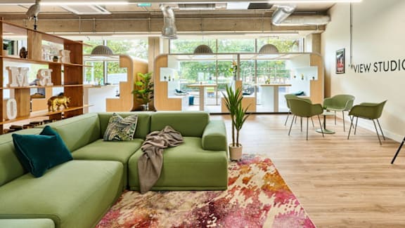 A living room with a green couch and a rug.