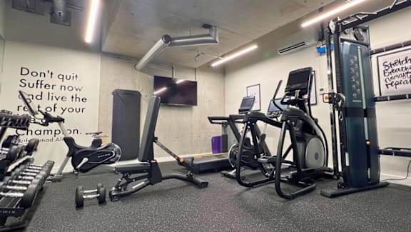 A gym with a sign that says "Don't quit, Suffer now and live the rest of your life as a champion.".