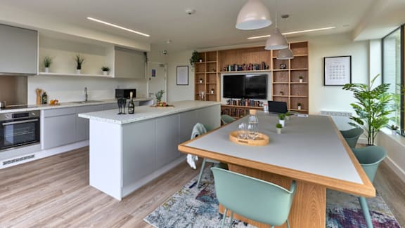 A modern kitchen with a wooden island and a dining table with chairs.