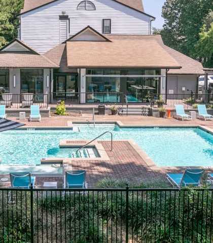 A pool with a fence around it and a house in the background.