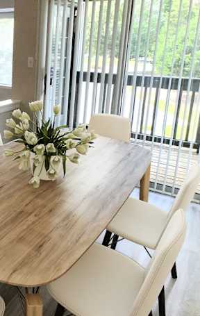 A dining room with a wooden table and white chairs.